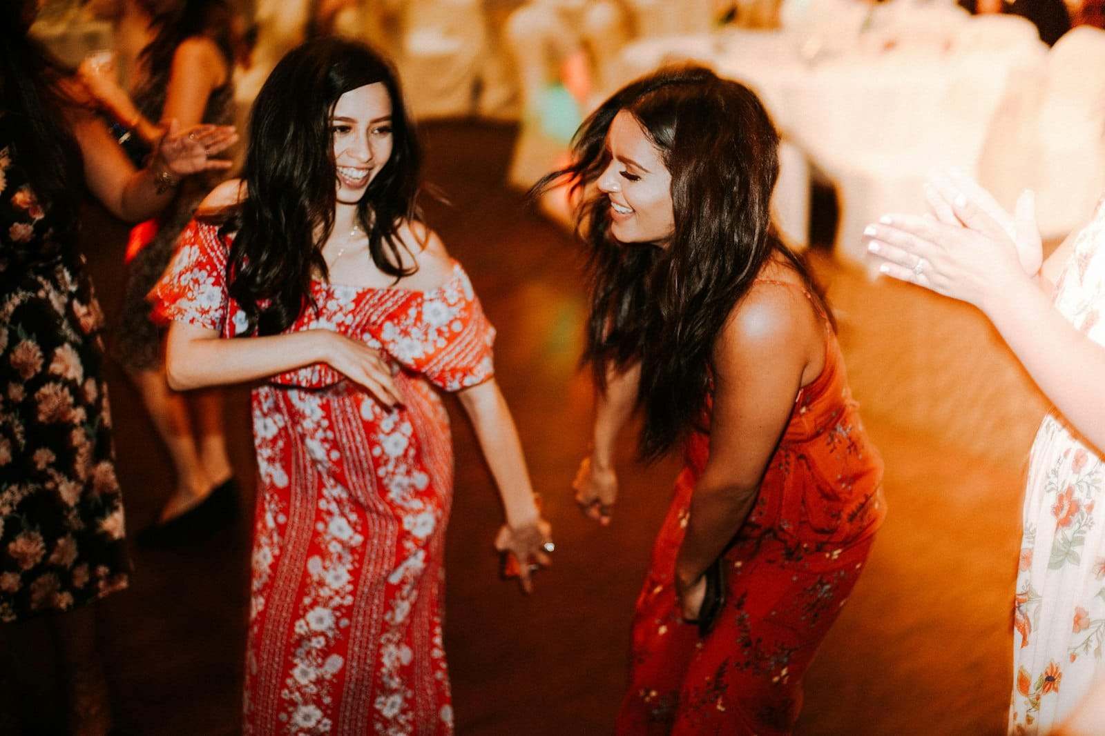 Two women laughing as they dance on a warm-lit floor