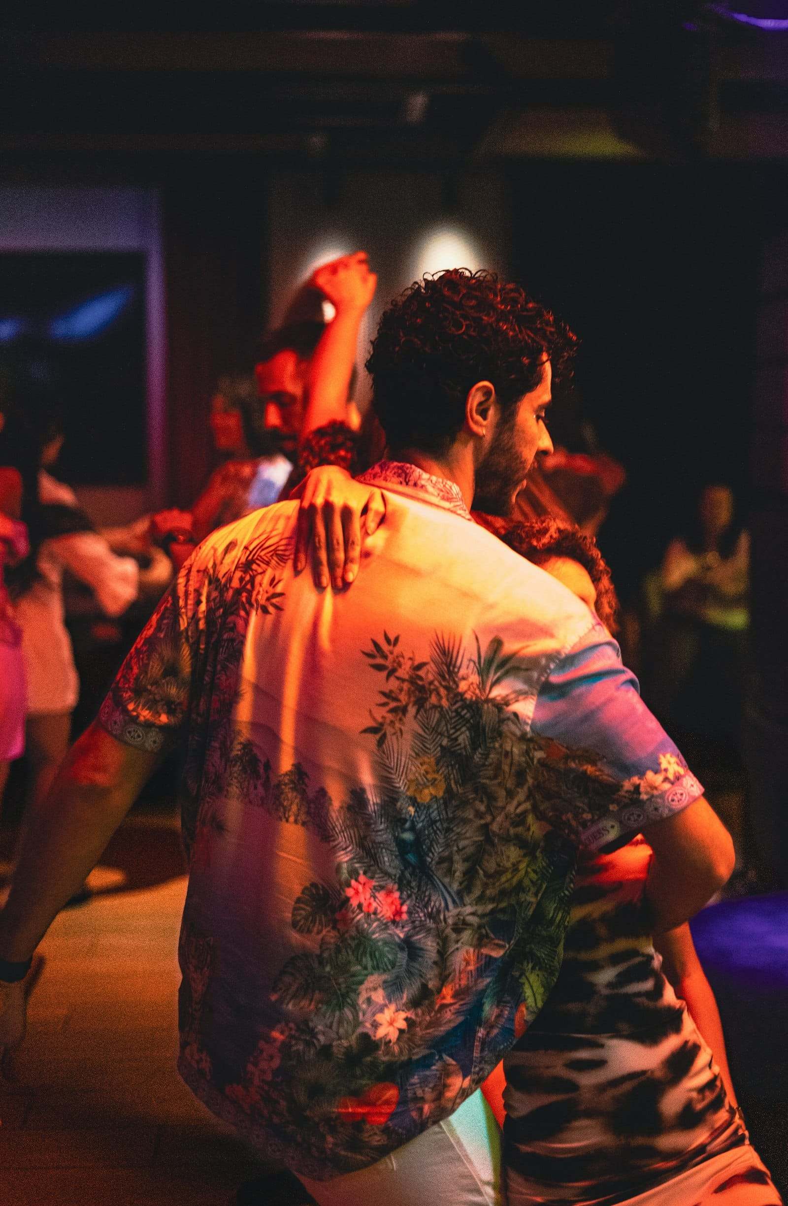 A couple dancing close in a warm, crowded room