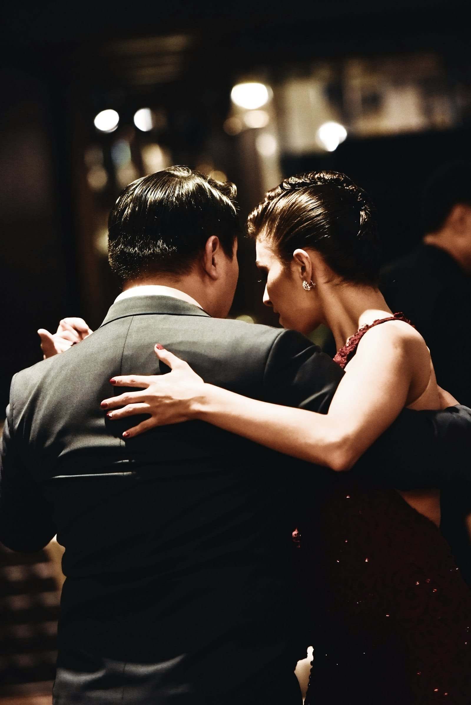 A couple in close hold, the woman in a red dress